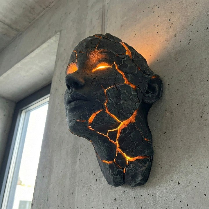 The Volcanic Face Lava Crack Wall Art Lamp glowing in a dark room