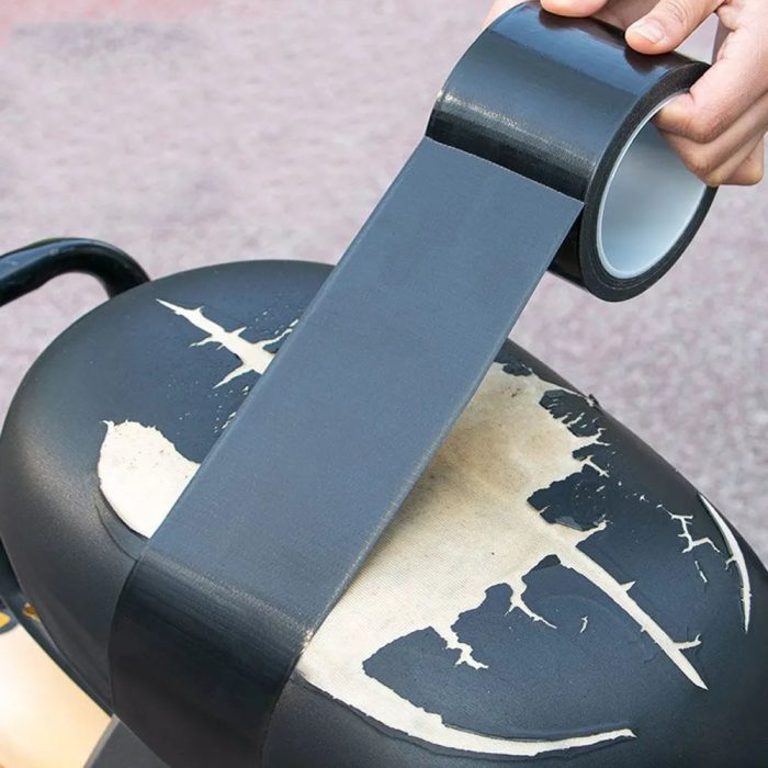 A swatch of Quick Fix Black Leather Furniture Repair Tape seamlessly covering a tear on a leather armchair.
