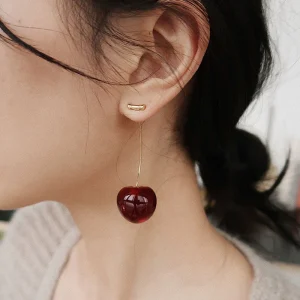 Vibrant red cherry fruit European style earrings hanging from a branch