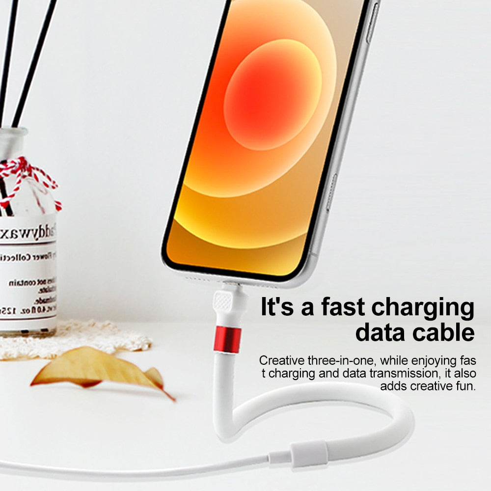 A smartphone being charged while held up by the bendable cable stand on a desk
