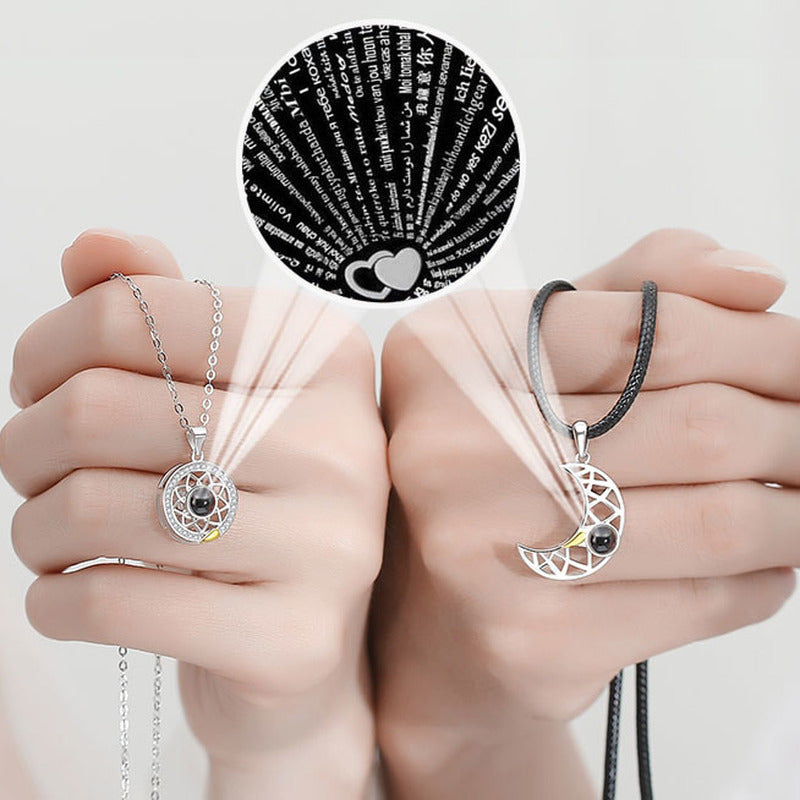 A couple holding hands while wearing the matching 100 Languages I Love You Projection Couple Necklace