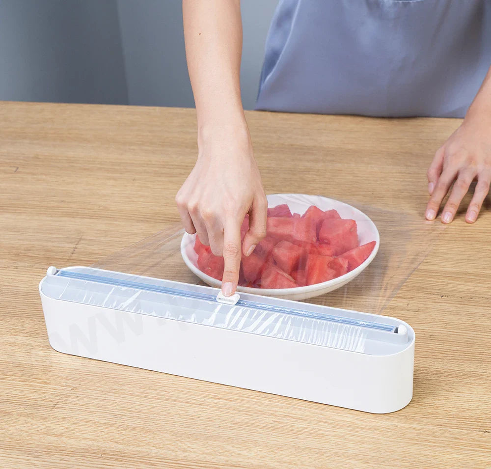 Magnetic kitchen film dispenser attached to a white refrigerator for easy access