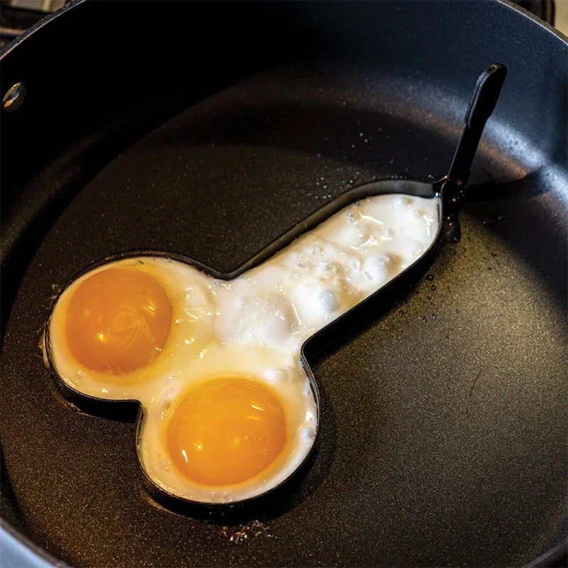 A person using the funny adult-theme egg frying mold in a pan