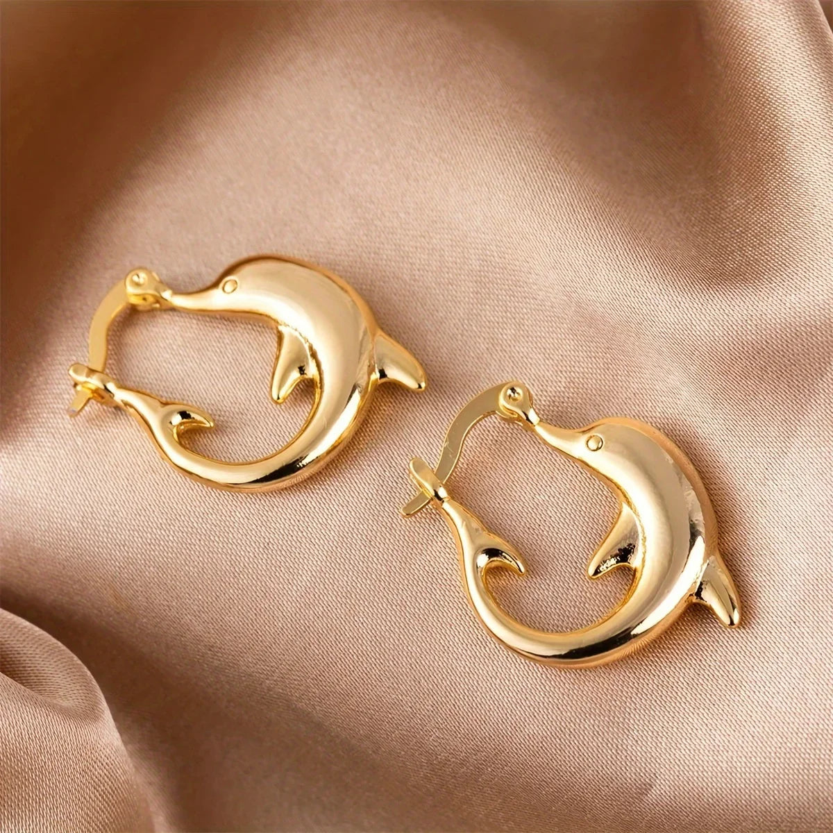 Dolphin Hoop Ocean Inspired Earrings shown on an ear for scale