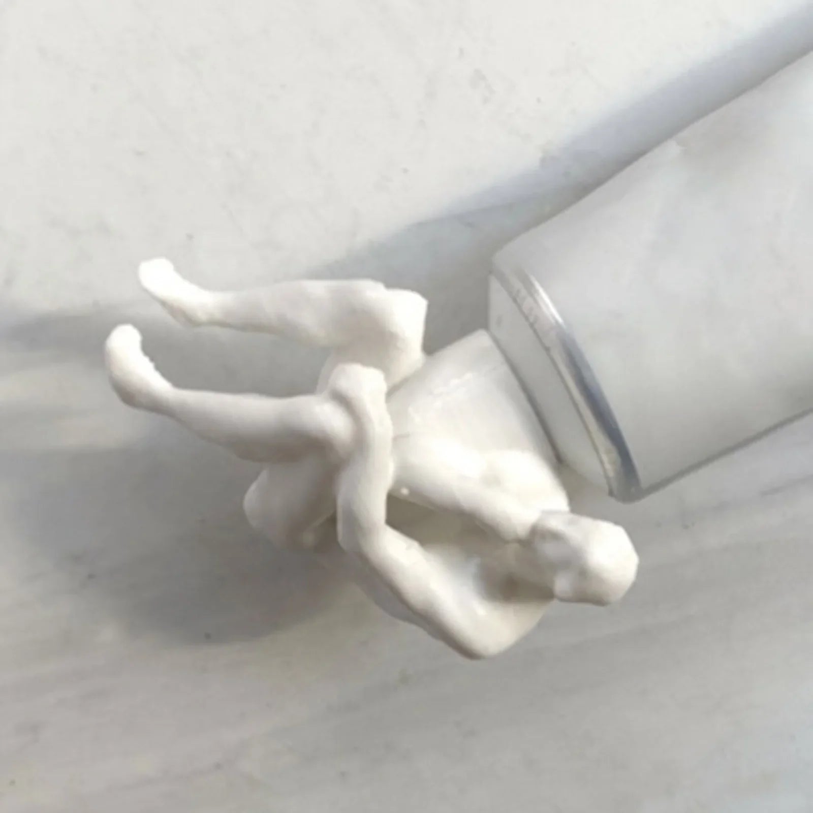 A person squeezing toothpaste from the funny dispenser cap